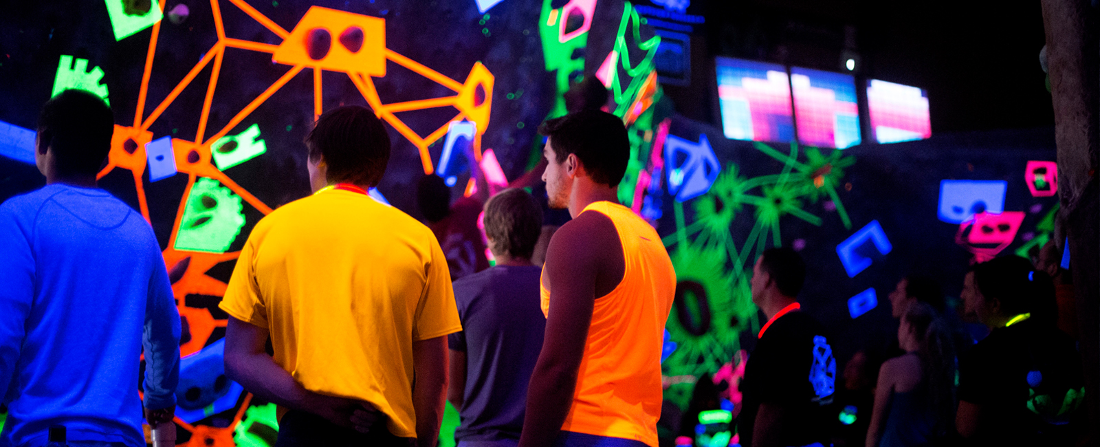 brightly dressed climbers in black light