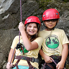 children wearing red helmets rock climbing outside