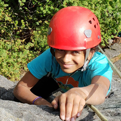 child wearing red helmet rock climbing outside