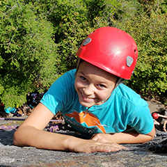 child wearing red helmet rock climbing outside