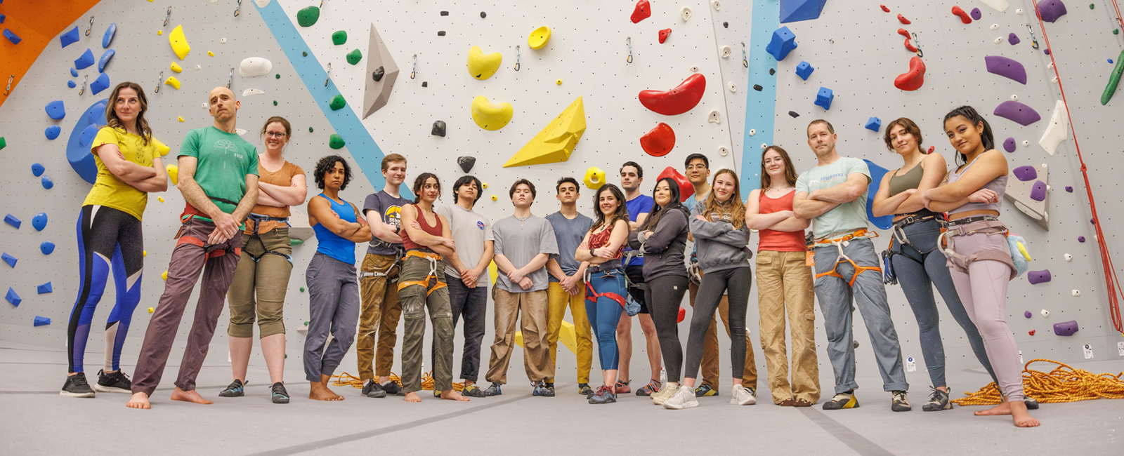 group of people posing in front of a climbing wall